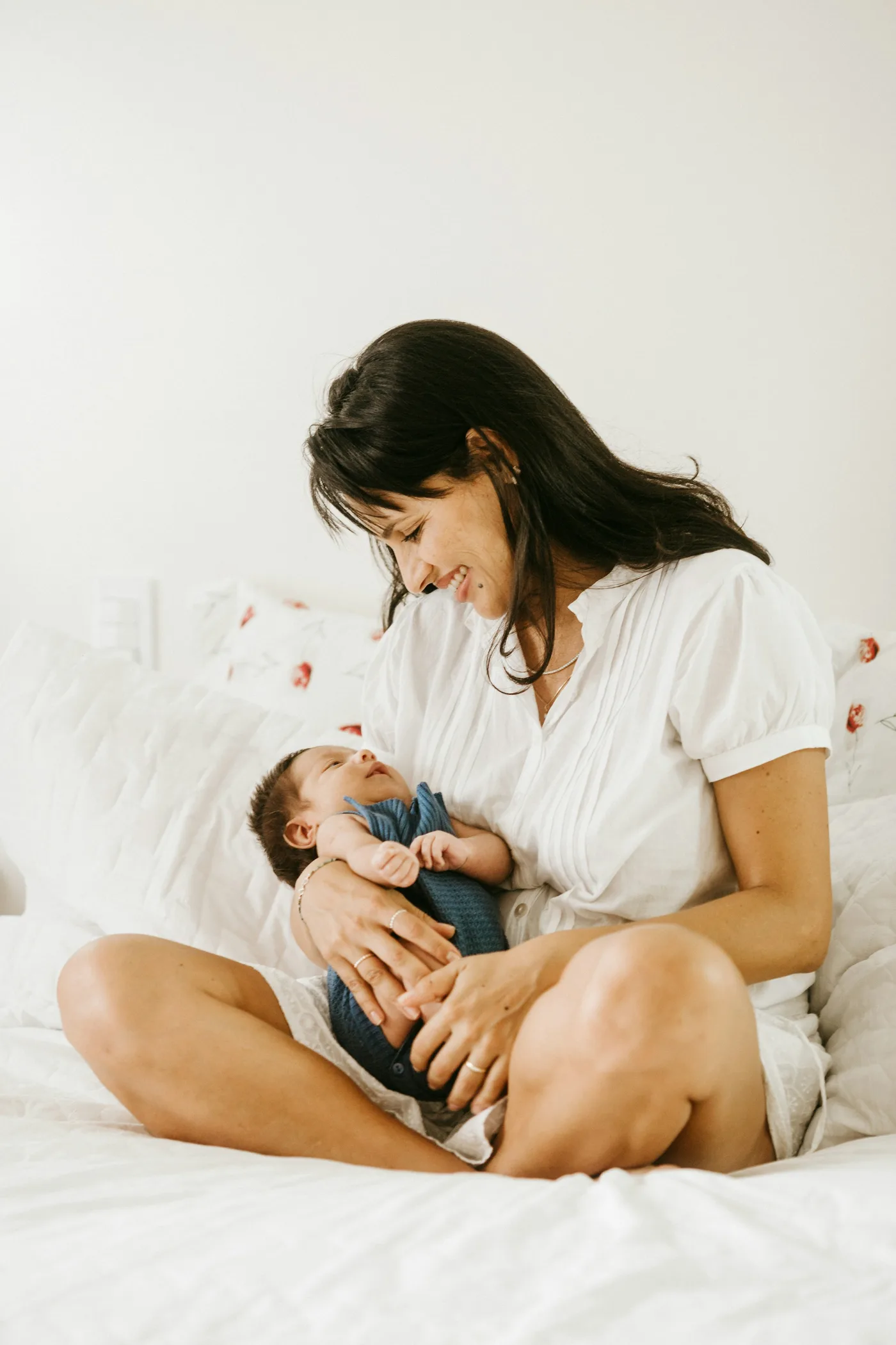 Mother smiling down at her newborn baby, soft natural light